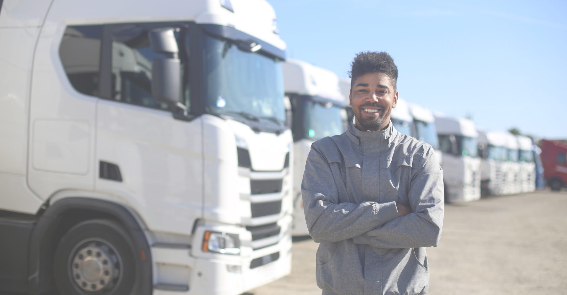 Profissional do transporte em frente a uma frota de caminhões